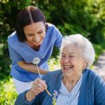 Female,Caregiver,And,Senior,Woman,In,Wheelchair,Holding,Dandelion,,Picking
